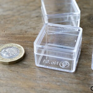 May include: Four clear plastic square boxes with lids. The boxes are stacked on top of each other. The boxes are labeled with the text "No. 3."