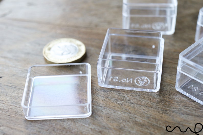 May include: Four clear plastic square boxes with a raised lip around the edge. The boxes are empty and have a small logo on the bottom that says "No. 2".