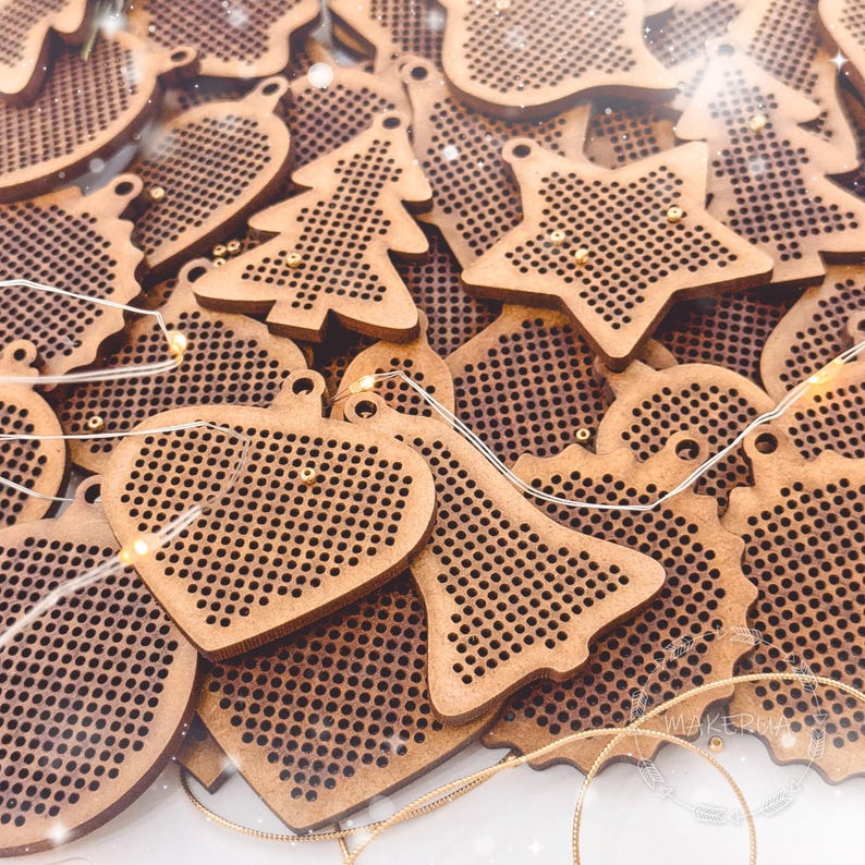 K&ouml;nnte beinhalten: Eine Sammlung von Holz-Weihnachtsschmuck in verschiedenen Formen, darunter Sterne, Herzen, Weihnachtsb&auml;ume und Glocken. Jeder Schmuck hat ein perforiertes Design und ein kleines Loch zum Aufh&auml;ngen. Die Ornamente sind hellbraun.