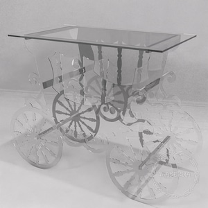 Könnte beinhalten: Ein klarer Beistelltisch aus Acryl in Form einer Pferdekutsche. Der Tisch hat eine rechteckige Glasplatte und aufwendige Ausschnitte des Karosserie, der Räder und der dekorativen Elemente der Kutsche. Das Design ist eine einzigartige Mischung aus Funktionalität und künstlerischem Flair.