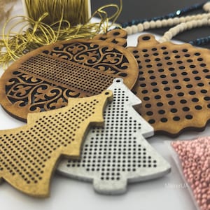 K&ouml;nnte beinhalten: Eine Sammlung von Holz-Weihnachtsschmuck in verschiedenen Formen, darunter ein runder Schmuck mit einem dekorativen Muster, ein Baum und ein Stern. Die Ornamente sind in Braun-, Gold- und Silbert&ouml;nen gehalten. Goldfaden und Perlen sind ebenfalls sichtbar.