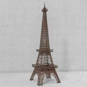Puede incluir: Una maqueta marrón de la Torre Eiffel con intrincados detalles de celosía. La torre tiene una base detallada, plataformas a media altura y una aguja puntiaguda. El modelo está hecho de un material marrón oscuro y se alza sobre una superficie blanca.