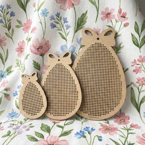 Könnte beinhalten: Drei eiförmige Kreuzstichrohlinge aus Holz mit bogenförmigen Oberteilen. Jeder Rohling hat ein Gitter aus kleinen Löchern für die Handarbeit. Die Rohlinge sind in verschiedenen Größen und aus hellbraunem Holz gefertigt.