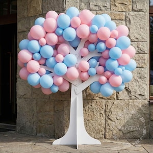 Puede incluir: Decoración en forma de árbol de madera blanca adornada con numerosos globos rosas y celeste claro. Los globos varían en tamaño, creando un dosel completo y redondeado. El árbol está colocado contra una pared de piedra, ideal para una fiesta.