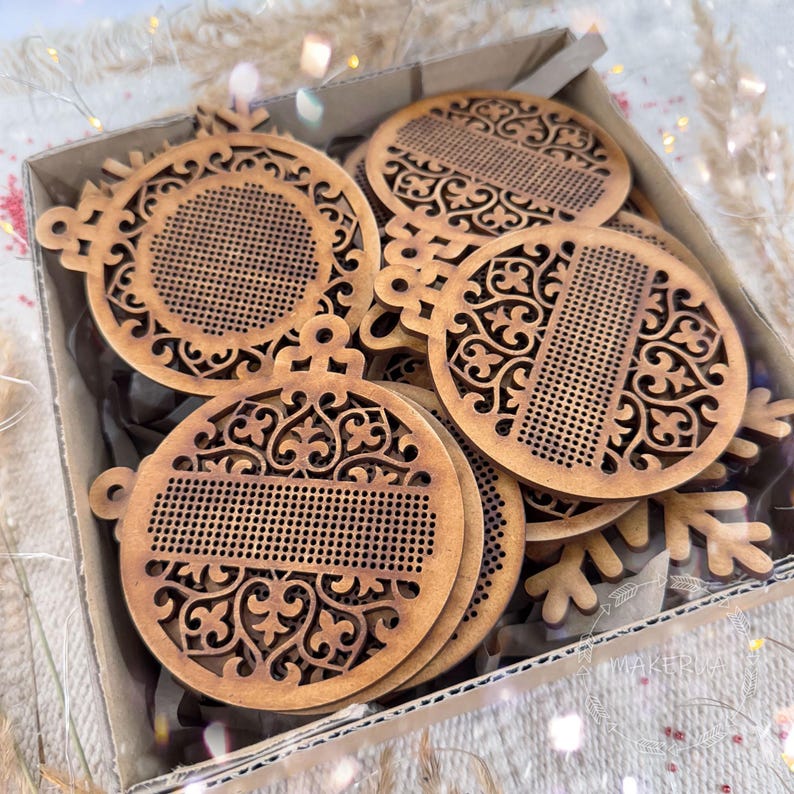 K&ouml;nnte beinhalten: Eine Sammlung lasergeschnittener Weihnachtsornamente aus Holz in einem Karton. Die Ornamente haben aufwendige, durchbrochene Designs und sind in einem nat&uuml;rlichen Holzton gehalten. Die Box ist mit mehreren Ornamenten gef&uuml;llt, was auf ein Bastel- oder DIY-Projekt hindeutet.