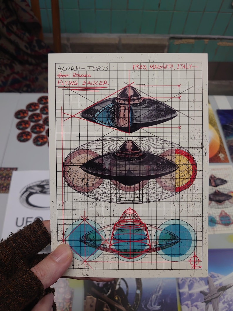 May include: A rectangular print on grid paper featuring technical illustrations of a flying saucer. Text reads ACORN + TORUS, 1933, MAGENTA, ITALY, and FLYING SAUCER. The design includes three stacked views of the craft with red and blue geometric overlays.