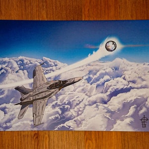 May include: A grey fighter jet flies through a cloudy sky with a bright white contrail behind it. A large, round, white object with a dark centre is visible in the upper right corner of the image.