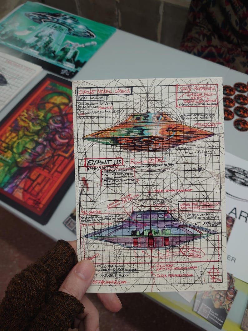 May include: A rectangular print featuring technical diagrams of a flying saucer, labeled Sport Model Specs, Bob Lazar, and Element 115. The artwork includes hand-drawn sketches, red and black grid lines, and handwritten notes on a cream-colored background.