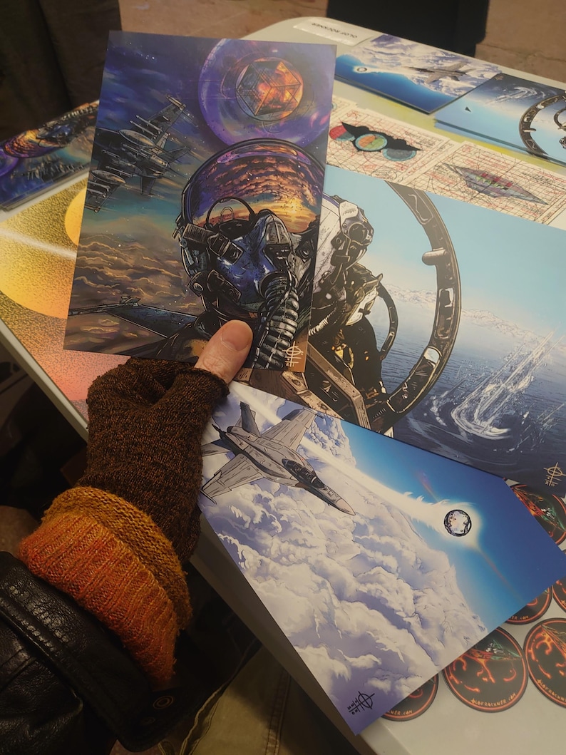 May include: A set of three colourful prints featuring a pilot in a cockpit, a fighter jet flying through clouds, and a geometric design with a galaxy background.