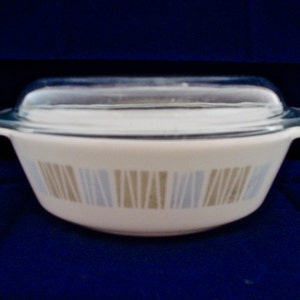 May include: A white oval baking dish with a glass lid. The dish has a brown and blue geometric pattern.