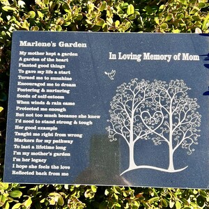 May include: A black granite plaque with white text and a white tree design. The text reads "Marlene's Garden" and includes a poem about a mother's love. The plaque also reads "In Loving Memory of Mom".