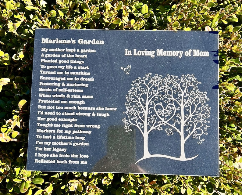 May include: A black granite plaque with white text and a white tree design. The text reads "Marlene's Garden" and includes a poem about a mother's love. The plaque also reads "In Loving Memory of Mom".