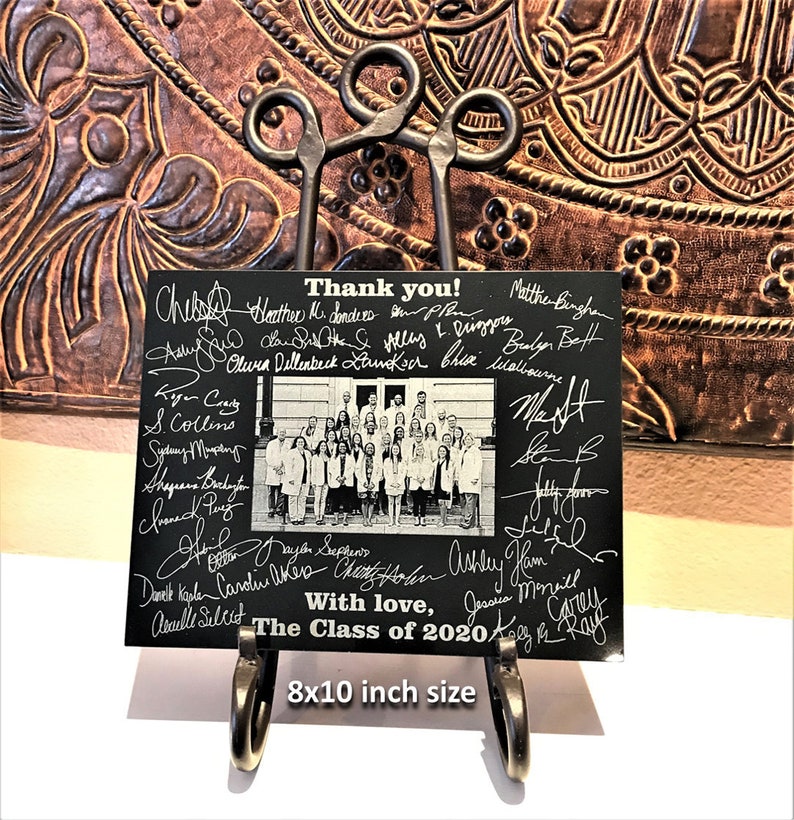 May include: Black and white photo of a group of people in white coats, with their signatures on a black background. The photo is framed with a black border and the text "Thank you! The Class of 2020 With love" is written below the photo.