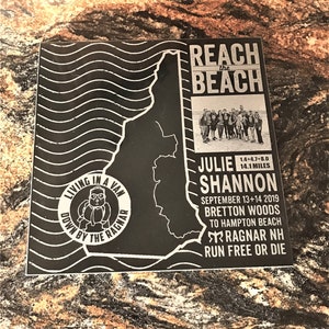 May include: Black and white image of a map of New Hampshire with the text "Reach the Beach" at the top. The text "Julie Shannon" is below the map, along with the text "September 13+14 2019", "Bretton Woods to Hampton Beach", "Ragnar NH", and "Run Free or Die".