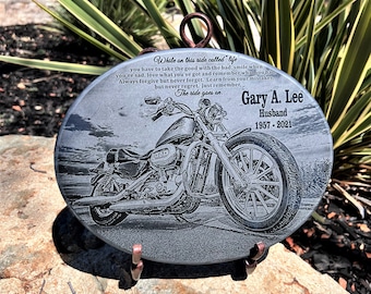 Puede incluir: Un memorial de piedra ovalada gris con una imagen grabada en blanco y negro de una motocicleta. La piedra tiene un soporte de metal y el texto "While on this ride called 'life' you have to take the good with the bad, smile when you're sad, love what you've got and remember what you had. Always forgive but never forget. Learn from your mistakes, but never regret. Just remember, The ride goes on. Gary A. Lee Husband 1957 - 2021" está grabado en la piedra.