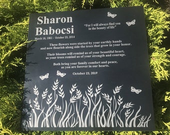 May include: Black granite memorial plaque with white engraved text. The text reads "Sharon Babocsi" with dates "March 18, 1961 - October 23, 2014" and "October 23, 2019". The plaque features a quote: "For I will always find you in the beauty of life". The plaque also features an engraved design of grass and butterflies.