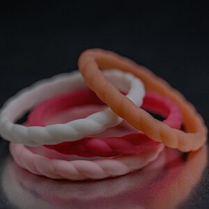 4 different styles of pink silicone bands in a braided style.