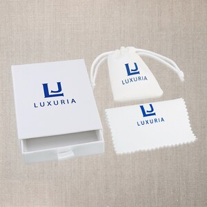 May include: White box with a drawer, a white drawstring bag, and a white polishing cloth. All three items have the same logo, a blue "LJ" with the word "LUXURIA" underneath.
