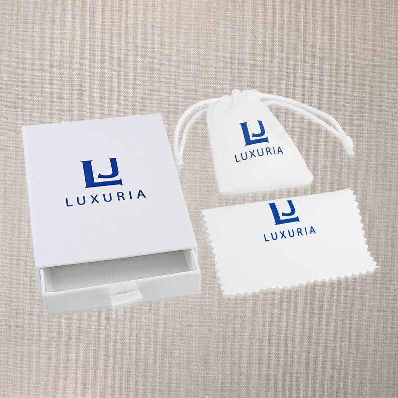 May include: White box with a drawer, a white drawstring bag, and a white polishing cloth. All three items have the same logo, a blue "LJ" with the word "LUXURIA" underneath.