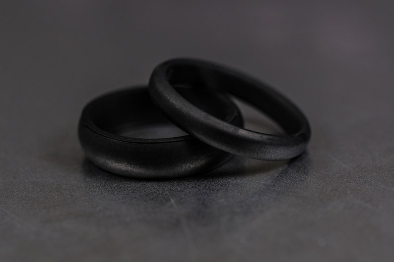 4 and 6mm black silicone bands unisex laying on each other with a dark background.