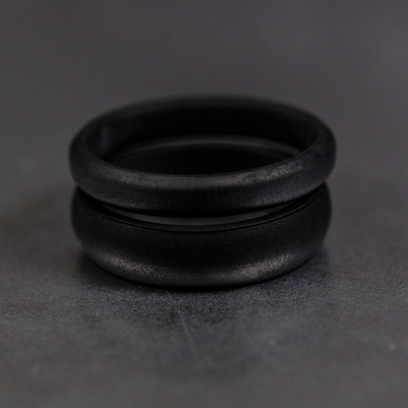 4 and 6mm black silicone bands unisex laying on each other with a dark background.
