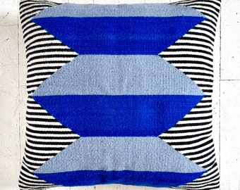 May include: A blue and gray geometric patterned throw pillow with black and white stripes on the back.