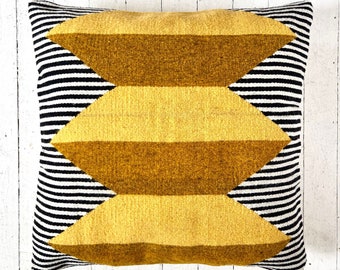 May include: A yellow and black geometric patterned throw pillow with a chevron design.