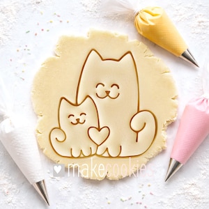 May include: A white ceramic mug with a black handle and the text "But First, Coffee" in a black, handwritten-style font. The mug is on a white surface.