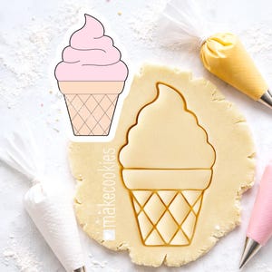 May include: An ice cream cone cookie cutter with a detailed design. The cutter is pressed into a piece of dough, next to a sticker of the ice cream cone. Piping bags with frosting are in the background. The sticker has a pink ice cream top.