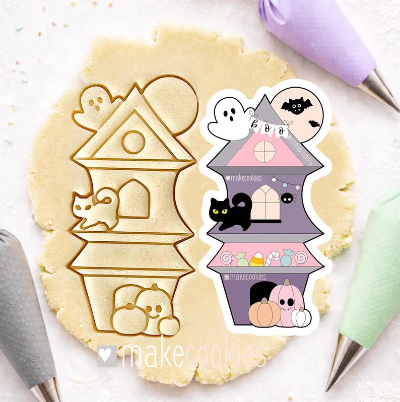 May include: Two Halloween-themed cookie cutters. One is a house-shaped cutter with a ghost, cat, and pumpkins. The other is a decorated house with a ghost, bat, and pumpkins. The cutters are on a sheet of dough.