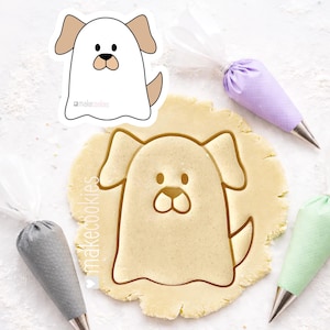 May include: A dog-shaped cookie cutter and a cookie cut-out. The cookie cutter is white with tan ears and a tan tail. The cookie cut-out is in the shape of the dog. Icing bags in gray, purple, and green are in the background.