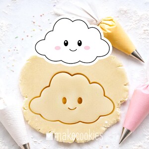 May include: A cloud-shaped cookie cutter with a smiling face, placed over a cut-out cloud shape in dough. The dough is light brown. The image includes a white cloud-shaped cookie cutter with a smiling face, and the text "makecookies".