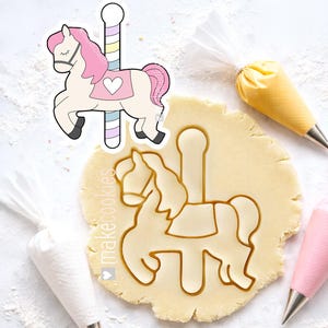 May include: A carousel horse cookie cutter with a pink mane and tail, a heart on its saddle, and a striped pole. The cutter is next to a cutout in dough and piping bags with frosting.