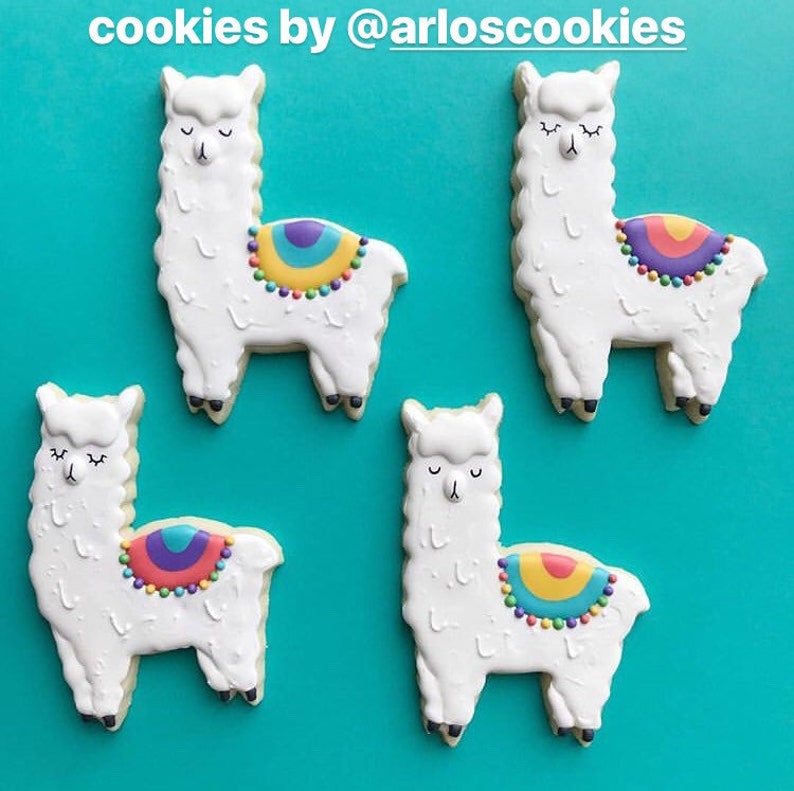 May include: Four llama-shaped cookies with white frosting and colorful saddle blankets. Each cookie has closed eyes and black feet. The cookies are decorated with rainbow-colored details and sit on a turquoise background. The text "cookies by @arloscookies" is at the top.