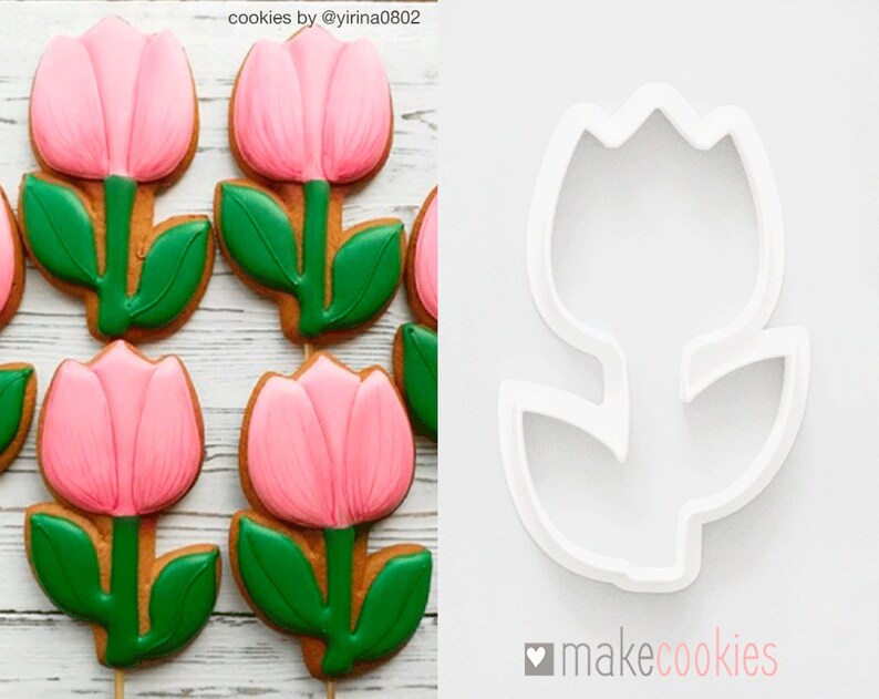 Op de afbeelding: Zes roze en groene suikerkoekjes in de vorm van tulpen, versierd met roze en groene glazuur. Naast de koekjes is een witte plastic koekjesuitsteker in de vorm van een tulp te zien. De tekst "makecookies" staat rechtsonder in de afbeelding.