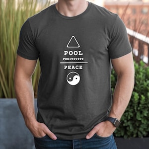 May include: Dark gray t-shirt with white text and graphics. The text reads "POOL POSITIVITY PEACE" with a triangle and yin-yang symbol. The shirt is a crew neck and appears to be made of a soft material.