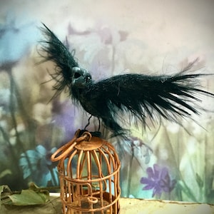 以下が含まれることがあります： さび付いた鳥かごの上に、頭蓋骨のような頭をした黒いカラスがとまっている。鳥かごはワイヤー製で、丸い天蓋が付いている。カラスの翼は広げられており、羽は黒い。