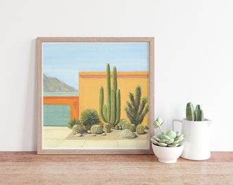 May include: A framed painting of a desert landscape with a yellow house and a variety of cacti. The house has a blue garage door and a red roof. The cacti are in front of the house and are surrounded by a brown dirt path.