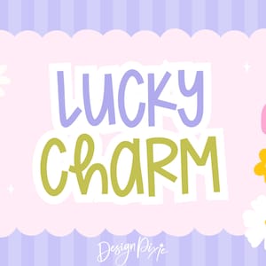 May include: A digital graphic with the words "LUCKY CHARM" in lavender and green, set against a pink scalloped frame. The background is striped in lavender and white, with daisy and heart accents.