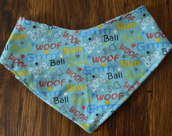 May include: A light blue dog bandana with a pattern of paw prints and the words "woof", "bone", "ball", "run", "bark", and "grrr".