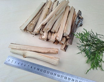 Könnte beinhalten: Ein Stapel dünner, hellbrauner Holzstäbchen, von denen einige übereinander gestapelt sind. Ein Lineal liegt neben den Stäbchen auf dem Tisch, mit den Zahlen 1 bis 22 sichtbar. Ein kleiner Zweig mit grünem Laub befindet sich rechts von den Stäbchen.