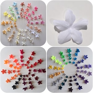 Puede incluir: Una colección de flores de tela de colores dispuestas en círculo, con una sola flor de tela blanca en el centro. Las flores están hechas de diferentes materiales y tienen una variedad de texturas.