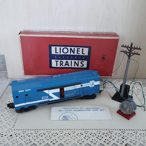 May include: A blue Lionel Electric Trains model train set with a generator car, a power pole, and a box with the text "Lionel Electric Trains".