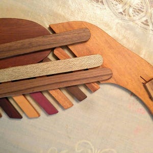 K&ouml;nnte beinhalten: Eine Holzskulptur eines Vogels, hergestellt aus verschiedenen Holzarten, mit einer nat&uuml;rlichen Holzveredelung. Der Vogel hat einen langen, gebogenen Schnabel und einen Fl&uuml;gel aus &uuml;bereinanderliegenden Holzst&uuml;cken.