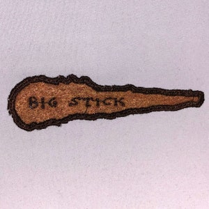 May include: Brown embroidered patch with the text "BIG STICK" in black thread.