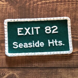 Puede incluir: Parche bordado verde y blanco con costuras blancas alrededor de los bordes. El parche dice "EXIT 82 Seaside Hts."