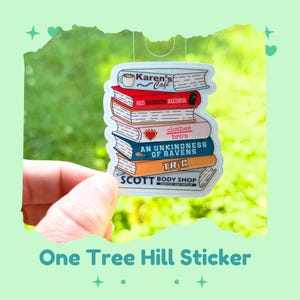 May include: A sticker featuring a stack of books with various titles, including "Karen's Cafe" and "Red Bedroom Records." The sticker has a white border and is held against a green background. The text "One Tree Hill Sticker" is at the bottom.