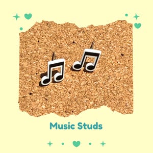May include: A pair of music note stud earrings. Each earring features a black and white musical note design. The earrings are displayed on a corkboard surface, with the text "Music Studs" below.