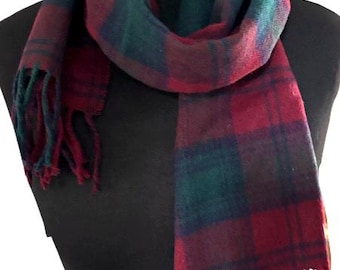 May include: A red and green plaid scarf with fringe on the ends. The scarf is folded and draped over a mannequin.