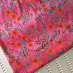 Peut inclure: Tissu rose avec un motif paisley et floral dans des tons d'orange, bleu et rouge.